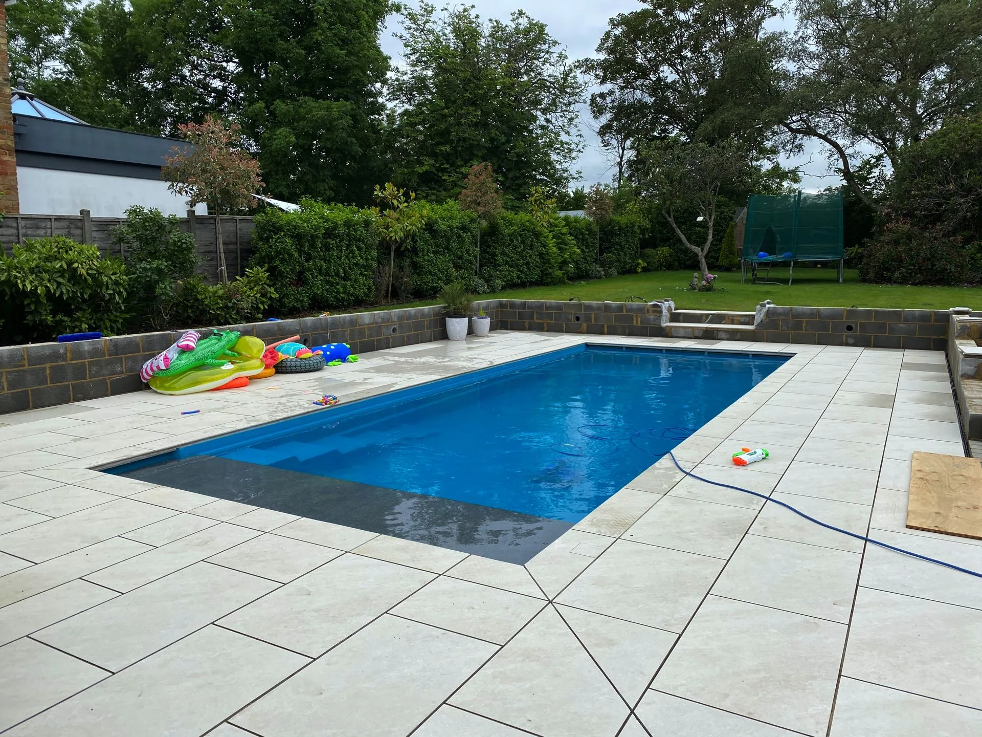 a pool with a hose and toys on the ground